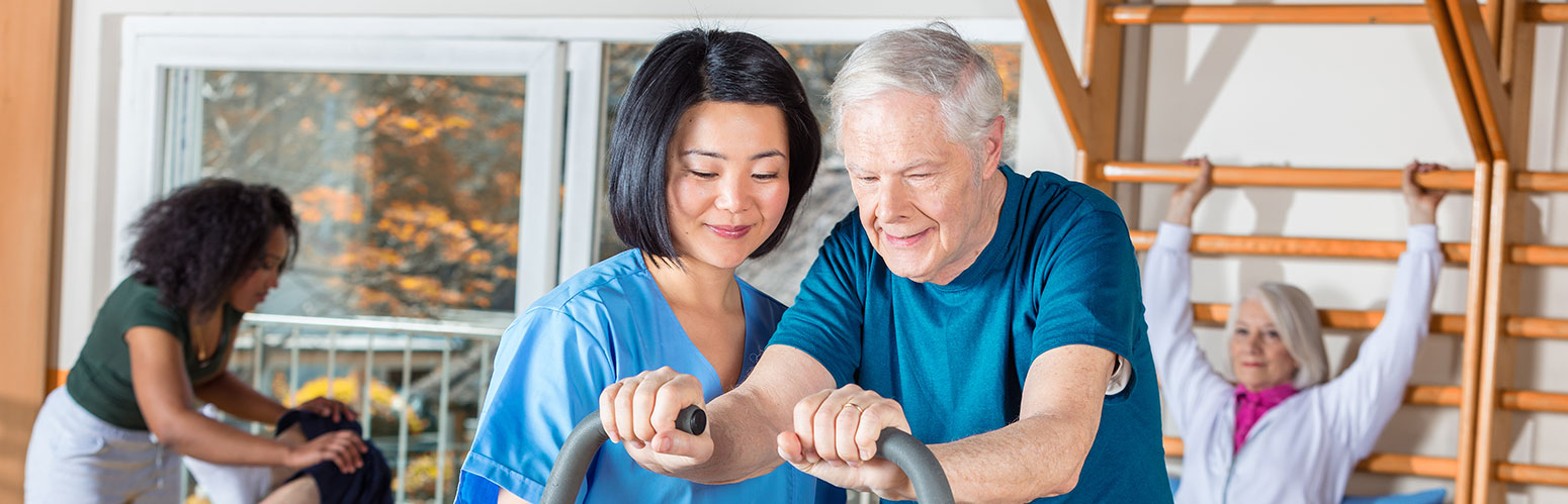 therpist working with elderly man on an exercise bike